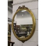 A gilt framed oval wall mirror.