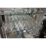 A quantity of good cut glass drinking glasses, a pair of candlesticks and a decanter.