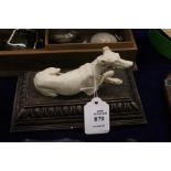 A model of a greyhound reclining on a carved wood base.