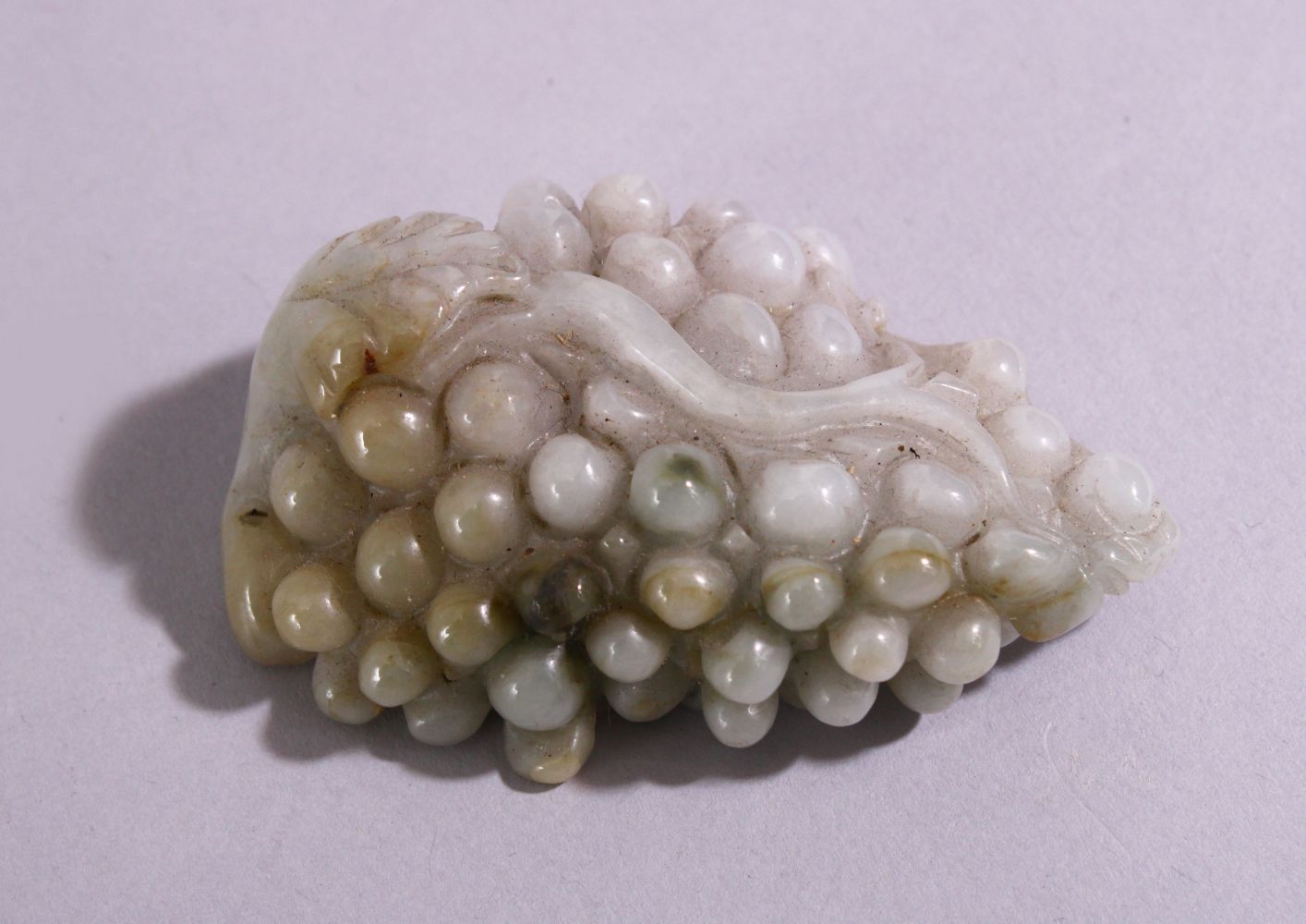 A CHINESE CARVED AND PIERCED JADITE / HARDSTONE AMULET, in the form of a bunch of grapes, 6.5cm x