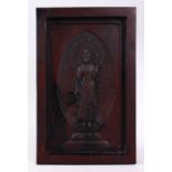 A 19TH CENTURY CHINESE CARVED WOODEN PANEL OF GUANYIN, stood amongst lotus and clouds, framed