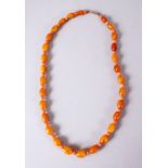 A CHINESE CARVED AMBER AND CORAL BEAD NECKLACE, with graduated oval beads and open measuring 47cm.