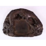 A 19TH CENTURY CHINESE SHAPED INKSTONE, carved with dragons, 23cm x 17cm.