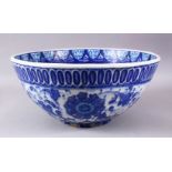 A LARGE 18TH CENTURY IZNIC POTTERY BOWL, with a blue ground decorated with white floral style