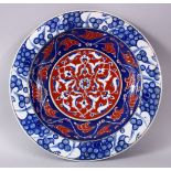 A RARE IZNIK POTTERY PLATE, decorated with blue, white and red decoration depicting stylized