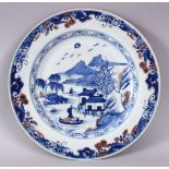 A CHINESE BLUE, WHITE & IRON RED PORCELAIN PLATE, decorated with native waterside landscape views