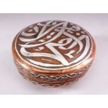 AN ISLAMIC CIRCULAR COPPER BOX AND COVER, the cover with silver inlaid calligraphy, 10cm diameter.