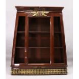 A RARE EGYPTIAN REVIVAL PAINTED OPEN FRONTED BOOKCASE of tapering form, the top with applied