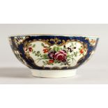 AN 18TH CENTURY WORCESTER BOWL painted with flowers in mirror panel on a blue scale ground.