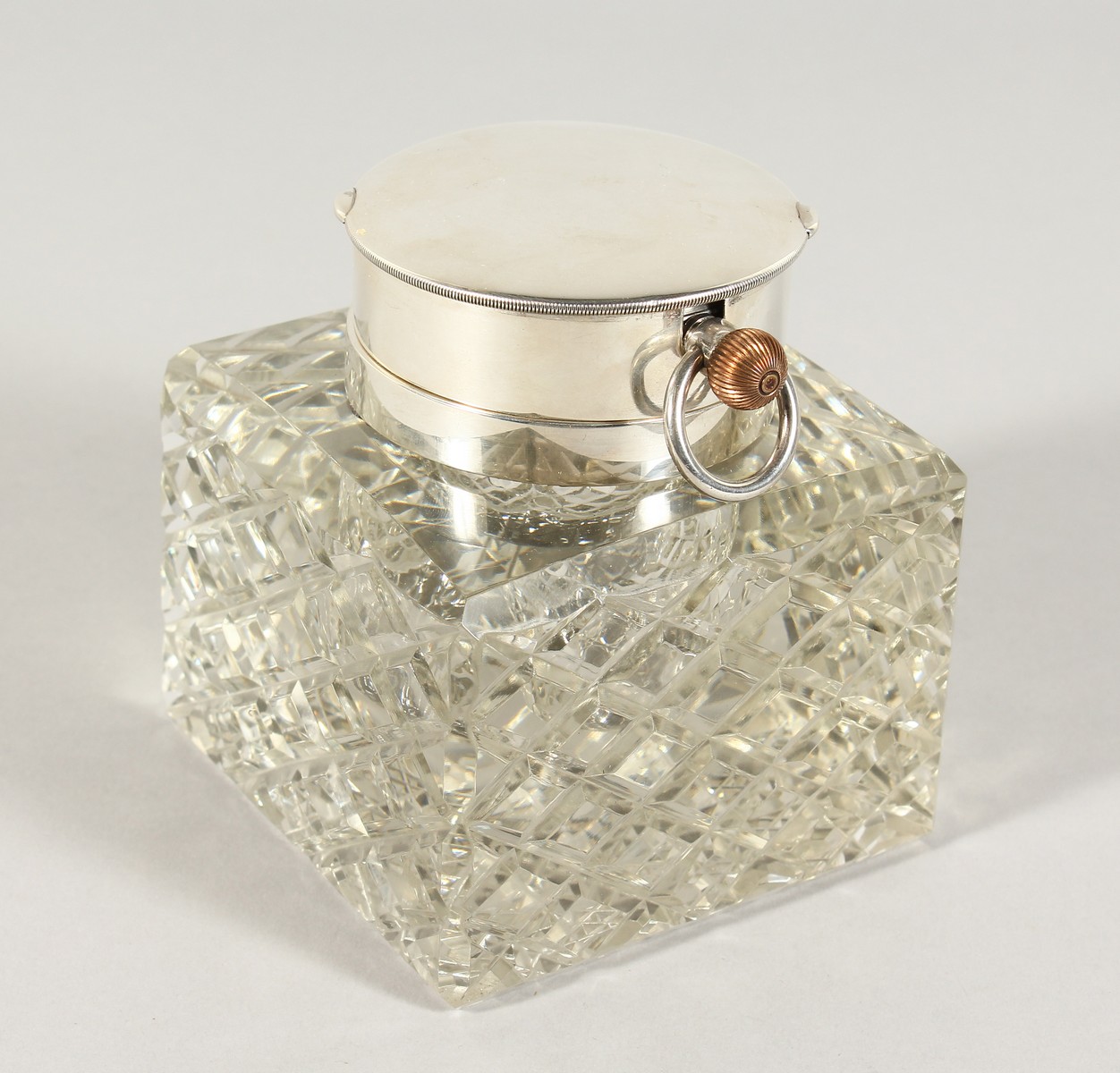 A SILVER AND CUT GLASS SQUARE INKSTAND, the top inset with a watch. 4ins square. London 1903.