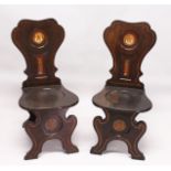 A VERY GOOD PAIR OF REGENCY MAHOGANY HALL CHAIRS, the shaped backs with painted crest on solid