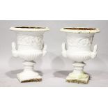 A PAIR OF WHITE PAINTED CAST IRON CAMPAGNA URNS. 2ft high.