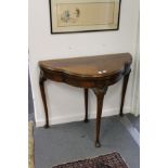 A mahogany shaped top foldover card table on carved cabriole legs.