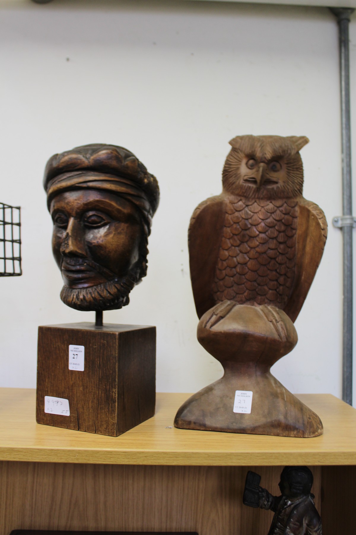 A carved wood bust and a carved model of an owl on a perch.