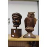 A carved wood bust and a carved model of an owl on a perch.