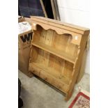A pine hanging shelf with three small drawers.