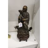 A Chinese bronze figure of a sage mounted on a Chinese hardwood stand.