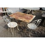 A painted wrought iron rectangular folding table with a set of four wrought iron chairs, two with