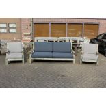 A large teak garden settee with a pair of lounger style armchairs with loose cushions.