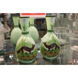 A pair of green opaque glass vases painted with foxes in a landscape.