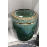 An unusual large green glazed pottery barrel shaped jar and cover, possibly Chinese.