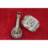 A small filigree model of a lute together with a napkin ring.