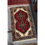 A small Persian rug, red ground with two geometric medalions.