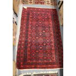 A Persian red ground rug with geometric decoration.