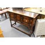 An oak sideboard with two panelled cupboard doors on turned legs, united by stretchers.