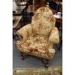 An Elizabethan revival upholstered walnut framed armchair with carved legs united by an X-shaped