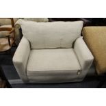 A modern large beige upholstered armchair with matching ottoman foot stool.