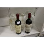 Two bottles of claret and three glass decanters.