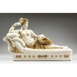 A POTTERY SEMI NUDE on a chaise longue, 15 ins. long