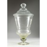 A LARGE PLAIN GLASS SWEETIE JAR AND COVER, 26 ins high.