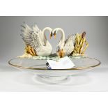 A GLASS CIRCULAR CENTREPIECE with two porcelain swans, 1 ft. 2 in.