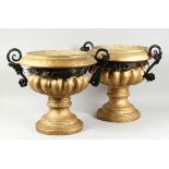 A PAIR OF GILDED CIRCULAR URNS with metal handles and circular bases, 1 ft. 7 in. high.