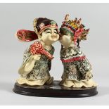 A JAPANESE STYLE POTTERY GROUP of two young children kissing, 7 in. high