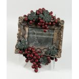 A SMALL MIRROR with fruiting vines in a composition frame, 14 in. x 10 in.