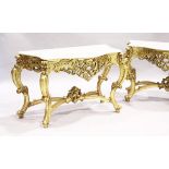 A PAIR OF GILDED AND MARBLE TOP CONSOLE TABLES with white speckled marble tops, gilt bases with