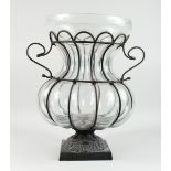 A LARGE SHAPED MOULDED GLASS BULBOUS VASE in a metal stand with square base, 20 ins high.