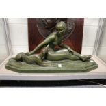 A good large green bronze patinated pottery Art Deco group of a seated female nude with a dog by her