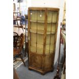 A good walnut display cabinet with central glazed door flanked by angled glazed sides.