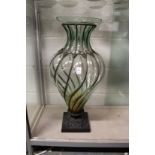 A large moulded glass and wrought iron pedestal vase.