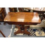 A 19th century mahogany foldover card table on an octagonal column with platform base and bun feet.