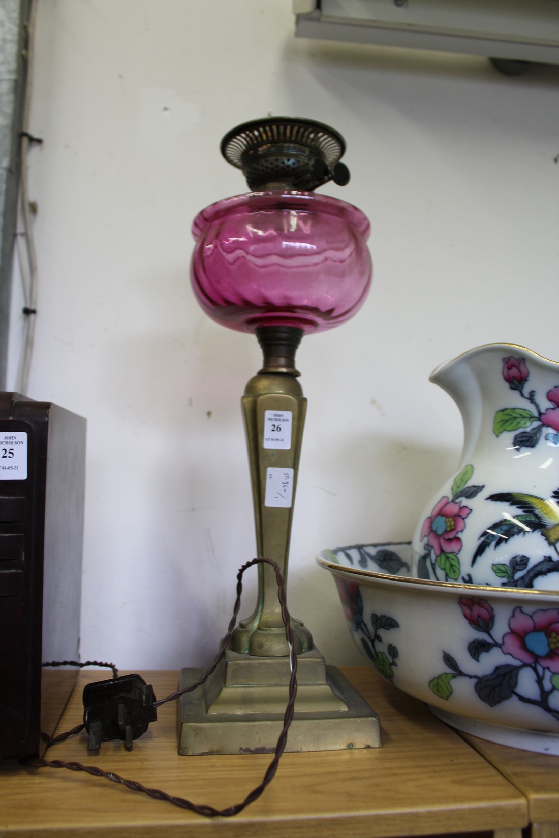 A brass oil lamp with cranberry coloured glass reservoir.