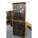 A large mahogany standing corner display cabinet.