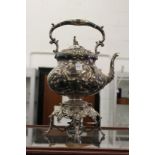 A good plated kettle on stand with embossed decoration, the lid having a Chinese man finial.