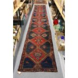 A Persian runner, dark red and blue ground with large diamond shaped motifs.