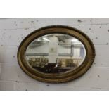 A gilt framed oval wall mirror.