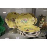 Seven yellow ground plates painted with flowers, with three matching serving dishes.